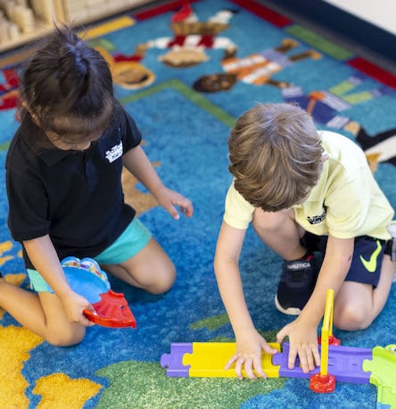 Two children in daycare playing with learning based toys.
